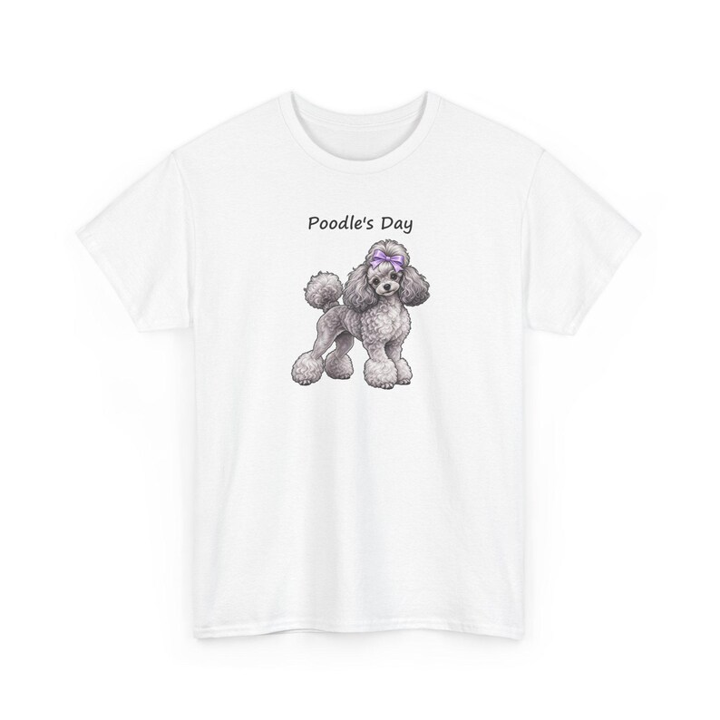 May include: A white short-sleeved t-shirt featuring a graphic of a grey poodle with a purple bow on its head. Above the poodle, the text Poodle's Day is printed in black. The shirt has a crew neckline and a standard fit.