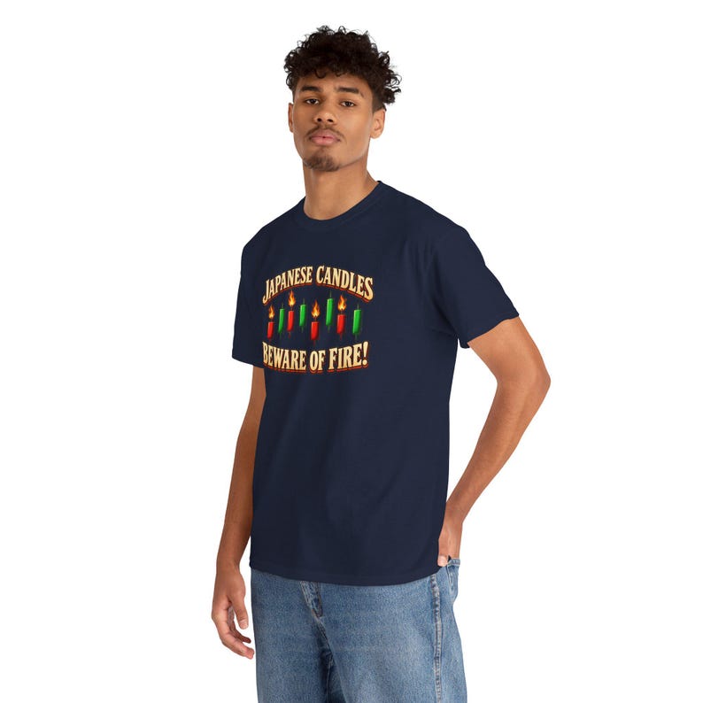 May include: A navy blue t-shirt featuring a graphic of red and green Japanese candlestick chart icons with flames on top. The text reads "JAPANESE CANDLES" above the icons and "BEWARE OF FIRE!" below in a bold, light-coloured font.