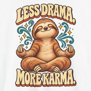 May include: A graphic print featuring a brown sloth sitting in a lotus position with eyes closed. The text "LESS DRAMA." appears above and "MORE KARMA." below in a retro font. Teal swirls and yellow stars surround the sloth.