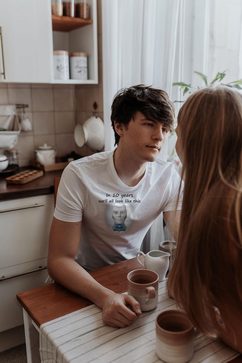 May include: A white short-sleeved t-shirt featuring a graphic of a robotic head centered on the chest. Above the graphic, the text reads, In 10 years we'll all look like this. The shirt has a crew neckline and a standard fit.