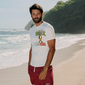 Op de afbeelding: Een wit T-shirt met korte mouwen met een afbeelding van een lopend persoon en de tekst I WAS BORN TO WALK NOT TO WORK, gecombineerd met een bordeauxrode short met een wit trekkoord en een klein wit logo op de linkerpijp.