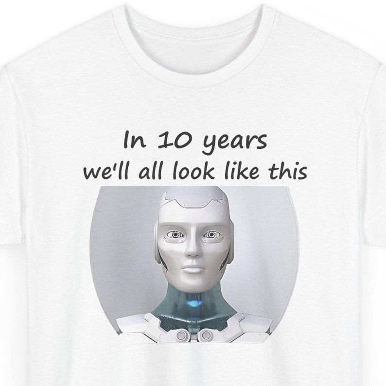 May include: A white t-shirt featuring a graphic of a silver and white humanoid robot head and shoulders. Above the robot, the text reads, In 10 years we'll all look like this, printed in a simple black sans-serif font on the front of the shirt.
