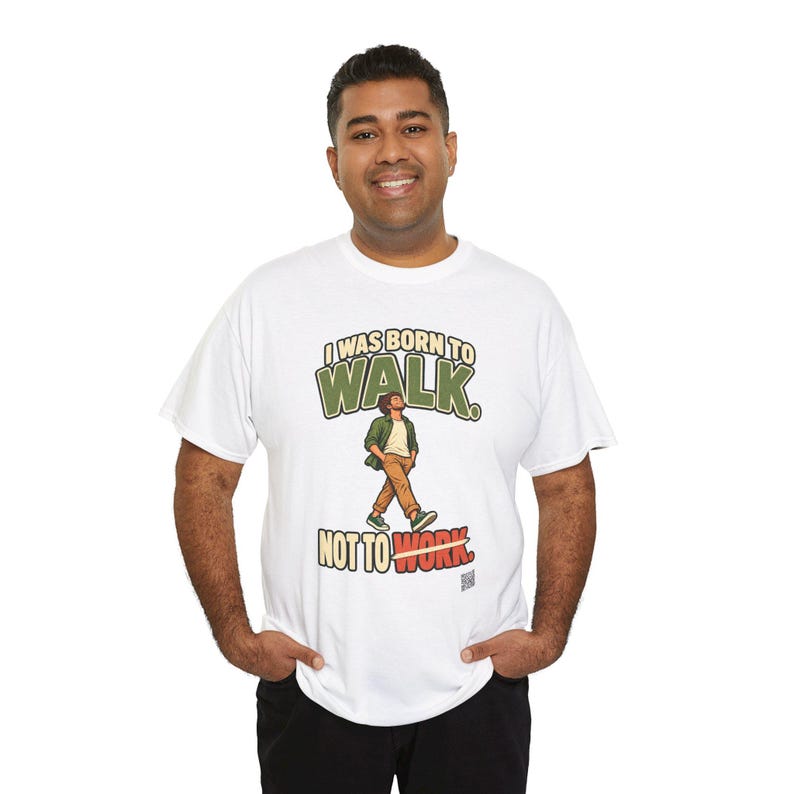 Op de afbeelding: Een wit t-shirt met korte mouwen en een afbeelding van een lopend persoon. De tekst luidt I WAS BORN TO WALK. NOT TO WORK. De afbeelding toont een persoon in een groen overhemd en een bruine broek, waarbij het woord WORK is doorgestreept met een gele lijn.