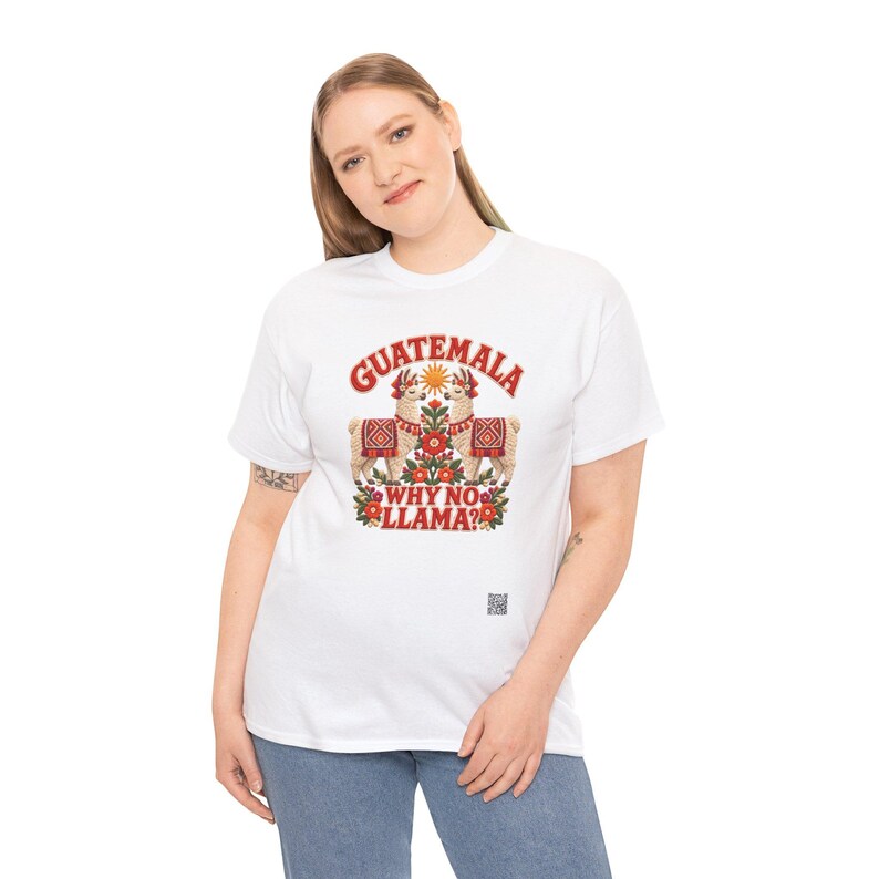 Puede incluir: Una camiseta blanca de manga corta con un gr&aacute;fico de dos llamas con mantas estampadas, un sol y elementos florales. El texto dice GUATEMALA WHY NO LLAMA? en letras rojas. Un peque&ntilde;o c&oacute;digo QR est&aacute; impreso cerca de la parte inferior derecha.