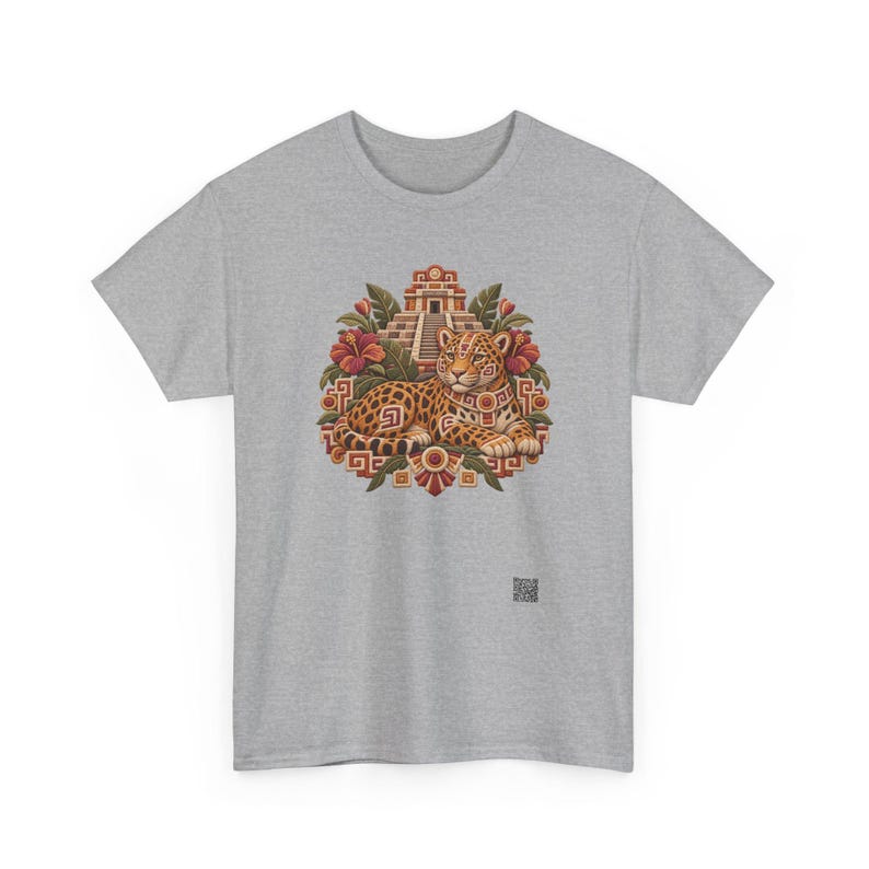 May include: A heather gray t-shirt featuring a central graphic of a spotted jaguar resting in front of a stepped pyramid. The design includes red hibiscus flowers, green leaves, and geometric patterns in shades of orange, brown, and gold.