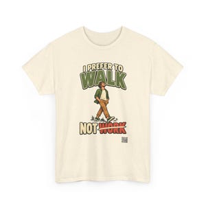 Op de afbeelding: Een cr&egrave;mekleurig T-shirt met korte mouwen en een afbeelding van een lopend persoon. De tekst I PREFER TO WALK staat boven de figuur en NOT WORK eronder, met een lijn door het woord WORK. Een kleine QR-code is rechtsonder afgedrukt.