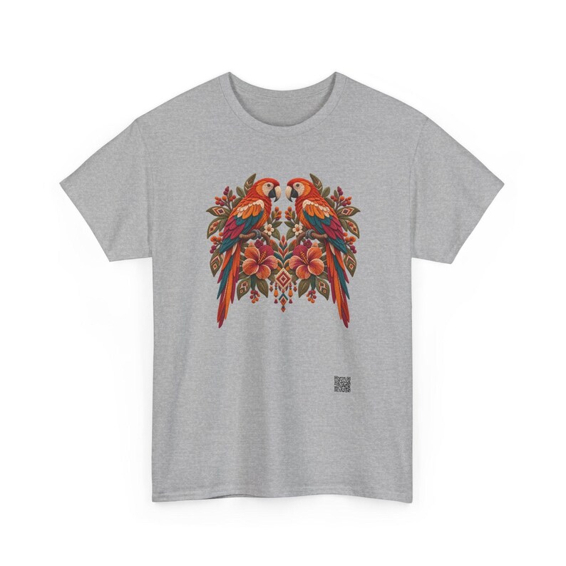 May include: A heather gray t-shirt featuring a central graphic of two symmetrical parrots perched among orange hibiscus flowers and green leaves. The design includes intricate geometric patterns and a small square QR code at the bottom right.