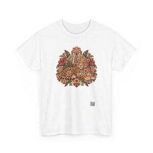 May include: A white short-sleeved t-shirt featuring a central graphic of a spotted jaguar resting in front of a stepped pyramid. The design includes red hibiscus flowers, green leaves, and geometric patterns in shades of brown, orange, and red.