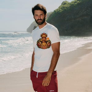 May include: A white short-sleeved t-shirt featuring a colorful graphic print of a figure in traditional feathered headdress and ornate attire, paired with solid maroon shorts that have a white drawstring and small white text on the leg.