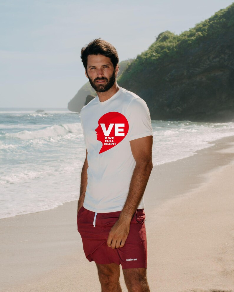 Puede incluir: Una camiseta blanca de manga corta con un gr&aacute;fico rojo en forma de coraz&oacute;n en el pecho con el texto VE R WE FULL HEART? y pantalones cortos granates con cord&oacute;n blanco y un peque&ntilde;o logotipo blanco en la pierna izquierda.