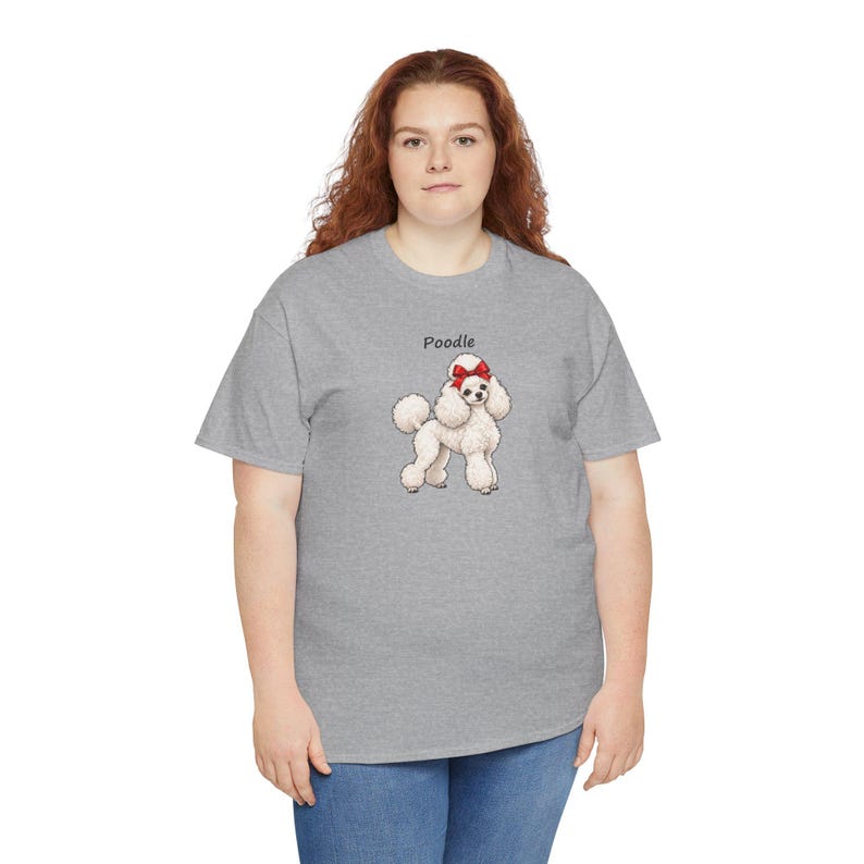 May include: A heather gray short-sleeve t-shirt featuring a graphic of a white poodle with a red bow on its head. The word Poodle is printed in black text above the dog illustration. The shirt has a crew neckline and a standard fit.