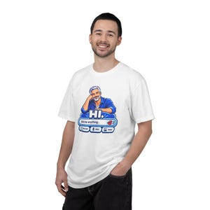 Może przedstawiać: Biały t-shirt z krótkim rękawem z grafiką przedstawiającą mężczyznę z siwymi włosami w niebieskiej koszuli. Poniżej znajduje się niebieskie okno czatu z napisem HI. Ask me anything... oraz ikonami czatu, głosu i obrazu z czerwonymi ustami.