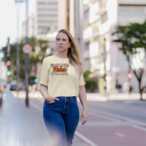 Puede incluir: Una camiseta de manga corta de color crema con el texto en negro y naranja "FEEL LIKE WORKING? Relax IT'LL PASS." La prenda tiene un cuello redondo y un dobladillo recto, confeccionada en una tela s&oacute;lida con un dise&ntilde;o sencillo.