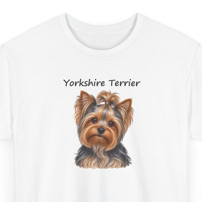 Op de afbeelding: Een wit t-shirt met een gedetailleerde illustratie van een Yorkshire Terri&euml;r met bruin en zwart haar, een klein staartje bovenop, en de tekst Yorkshire Terrier in zwarte letters boven de kop van de hond op de voorzijde.