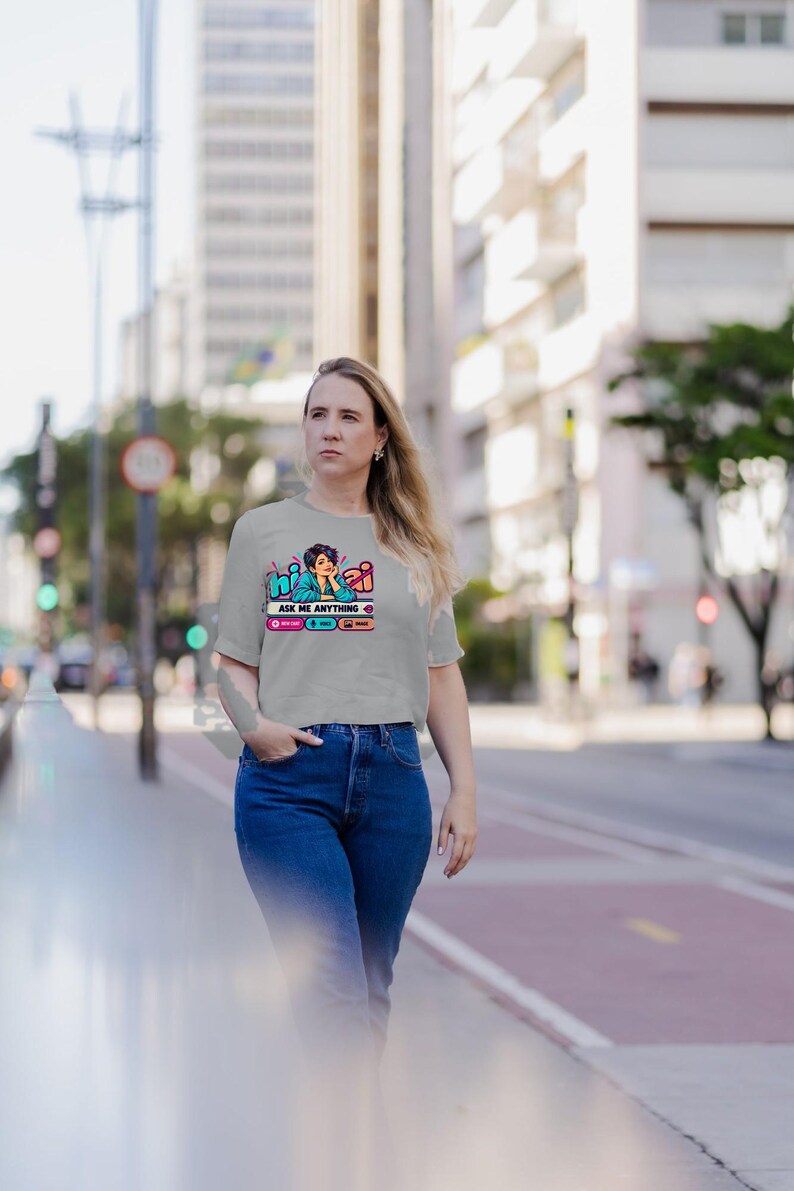 May include: A light gray short-sleeved t-shirt featuring a graphic print of a person with short dark hair resting their chin on their hand. The text reads hi ai and ASK ME ANYTHING, with small icons for chat, voice, and image functions below.