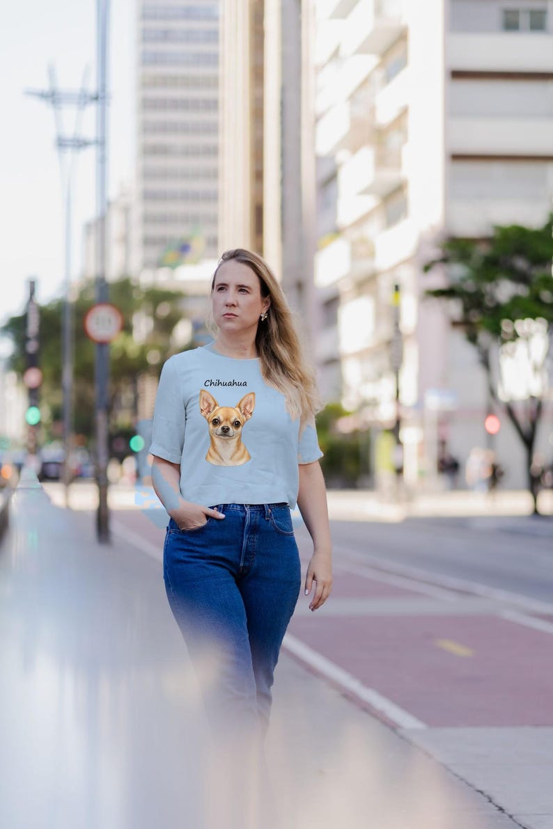 Puede incluir: Una camiseta de manga corta de color azul claro con una ilustraci&oacute;n gr&aacute;fica centrada de la cabeza de un perro Chihuahua de color canela con la palabra Chihuahua impresa en negro sobre las orejas.