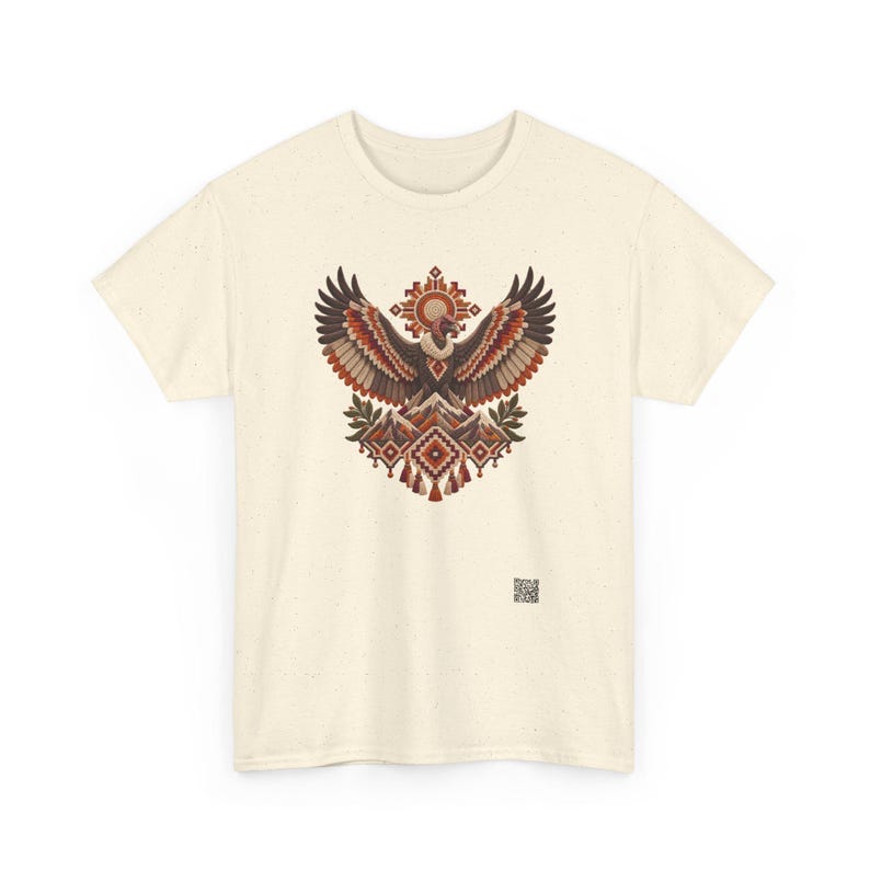 May include: A cream-colored short-sleeve t-shirt featuring a central graphic of a vulture with wings spread wide above stylized mountains and geometric patterns in shades of brown, orange, and red. A small QR code is printed near the bottom right.