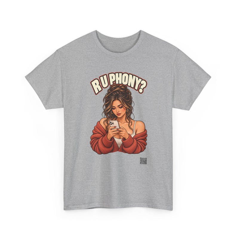 May include: A heather gray t-shirt featuring a graphic illustration of a person with long brown hair wearing a red cardigan over a white top, looking at a smartphone. Above the figure, the text reads R U PHONY? in a bold, arched font.