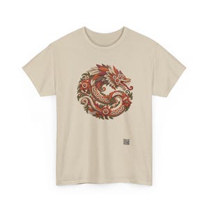 Puede incluir: Una camiseta beige de manga corta con un gr&aacute;fico circular de un drag&oacute;n estilizado entrelazado con elementos florales en tonos rojos, naranjas y marrones. El dise&ntilde;o incluye patrones geom&eacute;tricos y un peque&ntilde;o c&oacute;digo QR cuadrado debajo.