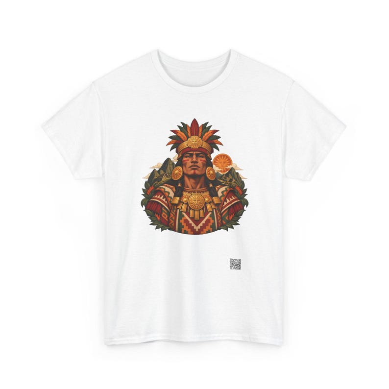 May include: A white t-shirt featuring a central graphic of a person wearing a feathered headdress and ornate gold jewelry. The design includes mountain silhouettes, a sun, and geometric patterns in red, green, and gold tones. A small QR code is visible below.