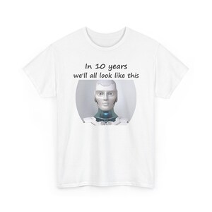 May include: A white short-sleeved t-shirt featuring a graphic of a silver and white humanoid robot head and shoulders. Above the robot, the text reads: In 10 years we'll all look like this. The design is centered on the chest of the garment.