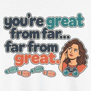 May include: A white t-shirt graphic featuring the text "you're great from far... far from great." in dark blue, teal, and orange. Below the text are four colorful footprints and an illustration of a person with brown hair holding binoculars.