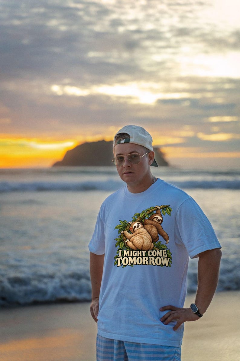 Pode incluir: Uma t-shirt branca de manga curta com um gr&aacute;fico de duas pregui&ccedil;as penduradas num ramo de &aacute;rvore e o texto I MIGHT COME TOMORROW impresso em letras amarelas a negrito por baixo da ilustra&ccedil;&atilde;o.