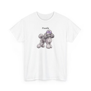 May include: A white short-sleeved t-shirt featuring a centered graphic of a grey poodle dog with a purple bow on its head. The word Poodle is printed in black text above the illustration of the dog, which has curly fur and a pom-pom tail.