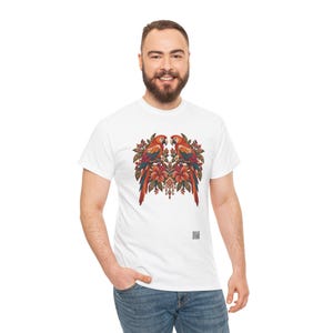 May include: A white short-sleeved t-shirt featuring a central graphic of two symmetrical parrots perched among orange hibiscus flowers and green leaves. The design includes intricate decorative patterns and a small QR code near the bottom hem.