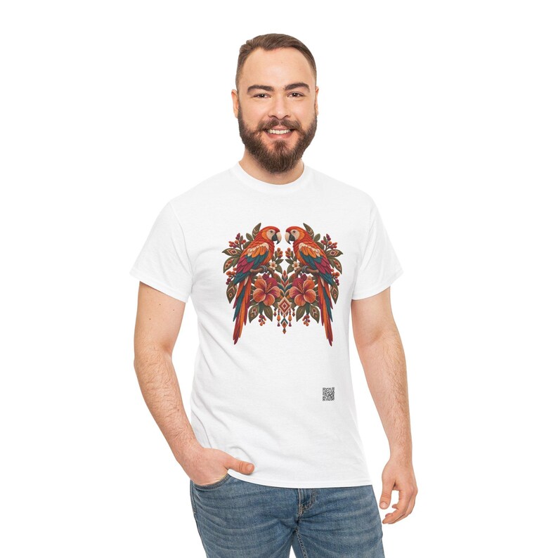 May include: A white short-sleeved t-shirt featuring a central graphic of two symmetrical parrots perched among orange hibiscus flowers and green leaves. The design includes intricate decorative patterns and a small QR code near the bottom hem.