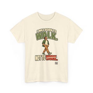 Op de afbeelding: Een cr&egrave;mekleurig t-shirt met korte mouwen en een afbeelding van een lopend persoon. De tekst luidt I WAS BORN TO WALK. NOT TO WORK. De persoon draagt een groen overhemd, een wit ondershirt en een bruine broek. Onderaan staat een QR-code.