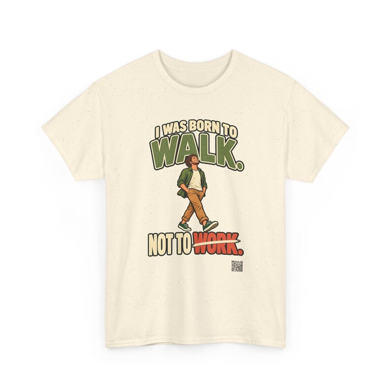 Op de afbeelding: Een cr&egrave;mekleurig t-shirt met korte mouwen en een afbeelding van een lopend persoon. De tekst luidt I WAS BORN TO WALK. NOT TO WORK. De persoon draagt een groen overhemd, een wit ondershirt en een bruine broek. Onderaan staat een QR-code.