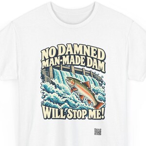 Puede incluir: Una camiseta blanca con un gr&aacute;fico de una trucha saltando sobre una presa con agua salpicando. El texto dice NO DAMNED MAN-MADE DAM WILL STOP ME! en letras negritas y curvas. Un peque&ntilde;o c&oacute;digo QR est&aacute; impreso en la parte inferior derecha.