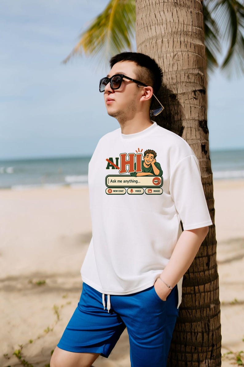 Puede incluir: Una camiseta blanca de manga corta con un estampado gr&aacute;fico de una interfaz de chat con el texto "AI HI" y "Ask me anything..." junto a iconos de chat, voz e imagen, combinada con pantalones cortos azules con cord&oacute;n.