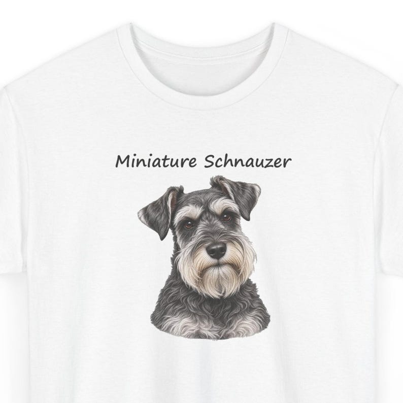 May include: A white t-shirt featuring a detailed illustration of a Miniature Schnauzer dog with black and grey fur and a light-colored beard. The text "Miniature Schnauzer" is printed in a simple black font above the dog's head.