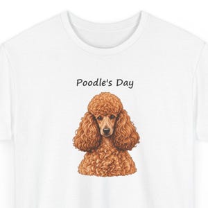 May include: A white t-shirt featuring a graphic illustration of a brown poodle with curly fur. Above the dog, the text Poodle's Day is printed in a simple black font. The design is centered on the chest of the shirt, showcasing the dog's detailed facial features and textured coat.