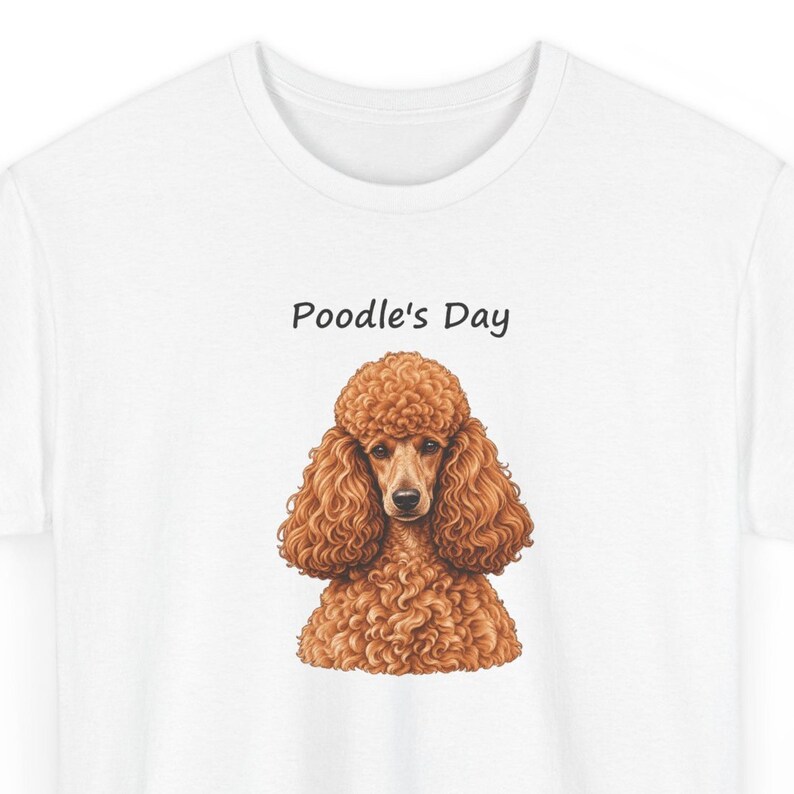 May include: A white t-shirt featuring a graphic illustration of a brown poodle with curly fur. Above the dog, the text Poodle's Day is printed in a simple black font. The design is centered on the chest of the shirt, showcasing the dog's detailed facial features and textured coat.