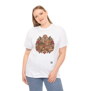May include: A white short-sleeve t-shirt featuring a central graphic of a spotted jaguar resting in front of a stepped pyramid, surrounded by tropical leaves and red flowers, with a small square QR code printed near the bottom right.