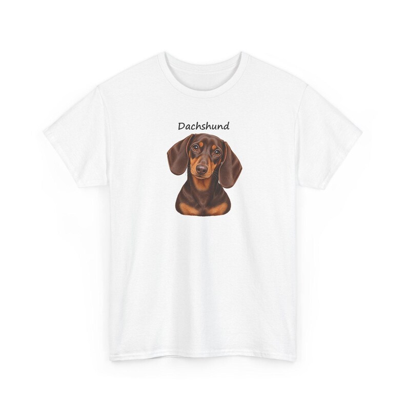 K&ouml;nnte beinhalten: Ein wei&szlig;es Kurzarm-T-Shirt mit einer zentralen Illustration eines braun-schwarzen Dackels. &Uuml;ber dem Kopf des Hundes ist das Wort Dachshund in einer einfachen schwarzen serifenlosen Schrift gedruckt. Das T-Shirt hat einen Rundhalsausschnitt.
