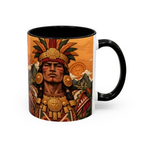 May include: A ceramic mug with a black handle and interior, featuring a colorful illustration of an indigenous person wearing a feathered headdress, gold circular earrings, and a detailed chest plate against a mountain landscape background.