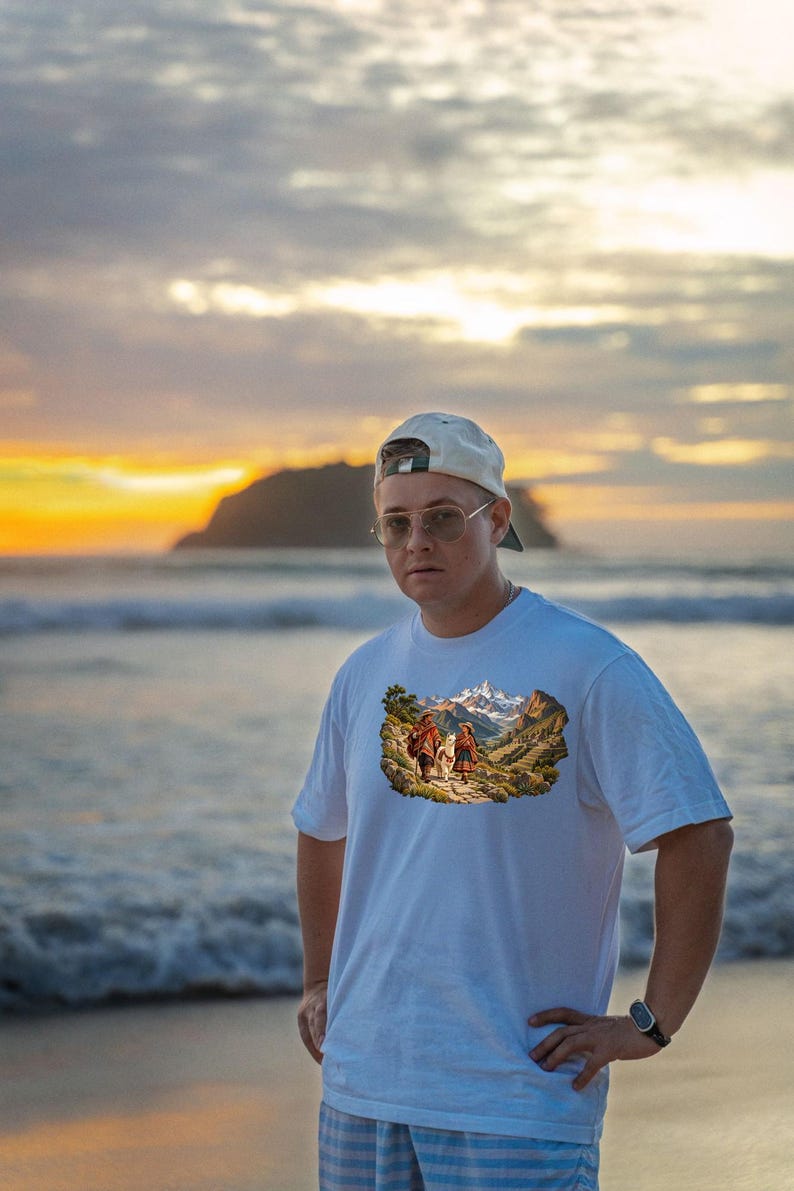 Puede incluir: Una camiseta blanca de manga corta con un estampado gr&aacute;fico rectangular de dos figuras caminando con una llama a trav&eacute;s de un paisaje monta&ntilde;oso con picos nevados, usada con una gorra de b&eacute;isbol de color claro y gafas.