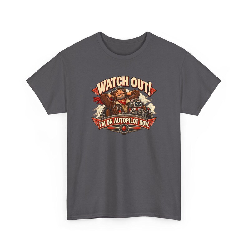 May include: A charcoal gray t-shirt featuring a graphic of a pilot with hands behind their head and a small robot in a cockpit. The text reads WATCH OUT! I'M ON AUTOPILOT NOW. The design includes red wings and a propeller emblem at the base.