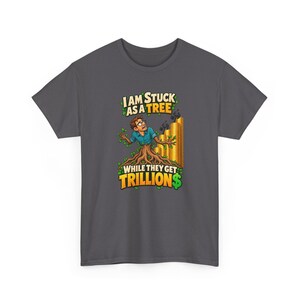 May include: A dark gray t-shirt featuring a graphic of a person with brown hair and glasses emerging from a tree trunk. Beside them are stacks of gold coins with small figures climbing them. The text reads: I AM STUCK AS A TREE WHILE THEY GET TRILLION$.
