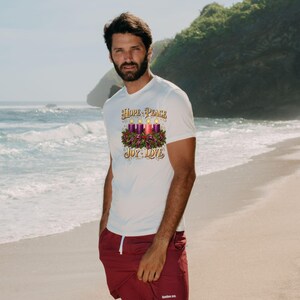 May include: A white short-sleeve t-shirt featuring a graphic of an Advent wreath with four lit candles and the text HOPE PEACE JOY LOVE in gold lettering. The shirt is paired with solid maroon shorts that have a white drawstring and small logo.