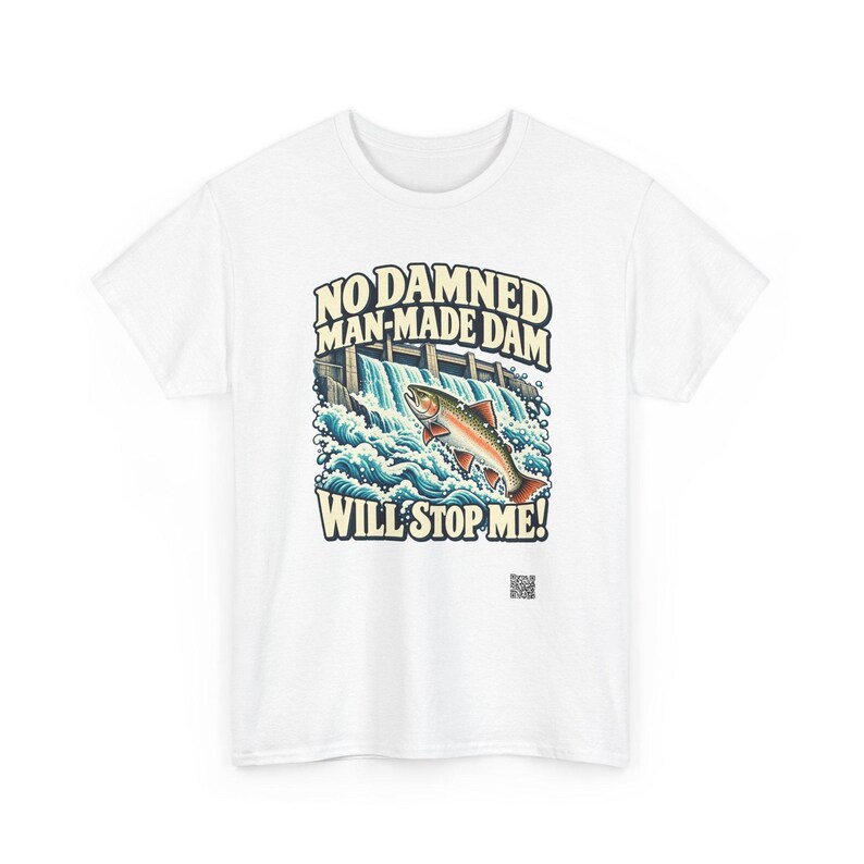 Puede incluir: Una camiseta blanca con una ilustraci&oacute;n gr&aacute;fica de un pez saltando sobre una presa con agua salpicando. El texto NO DAMNED MAN-MADE DAM WILL STOP ME! aparece en una fuente de color crema. Un peque&ntilde;o c&oacute;digo QR est&aacute; impreso bajo el gr&aacute;fico.