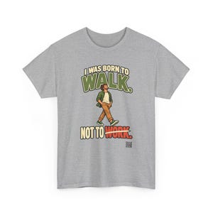 Op de afbeelding: Een grijs gem&ecirc;leerd t-shirt met een afbeelding van een lopend persoon. De tekst erboven luidt I WAS BORN TO WALK. en de tekst eronder luidt NOT TO WORK. De persoon draagt een groen overhemd, wit ondershirt, bruine broek en groene sneakers.