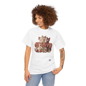 May include: A white short-sleeve t-shirt featuring a graphic print of three alpacas adorned with colorful patterned blankets and tassels. The alpacas are surrounded by small red and white flowers, and a small QR code is printed below the graphic.