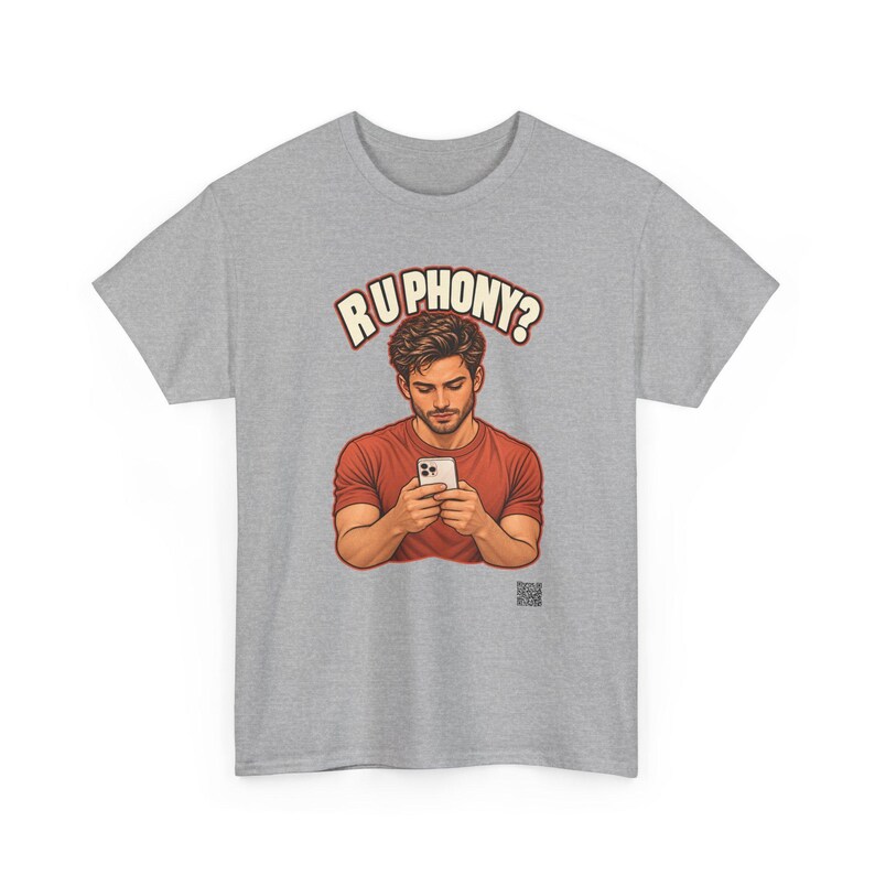 May include: A heather gray short-sleeve t-shirt featuring a graphic of a person in a red shirt looking down at a white smartphone. Above the figure, the text reads R U PHONY? in bold, cream-colored letters with a dark outline.