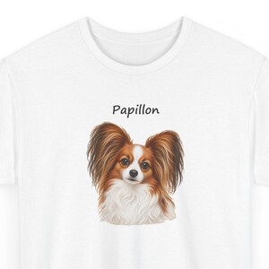Puede incluir: Una camiseta blanca con una ilustraci&oacute;n detallada de un perro Papillon con pelaje largo y fluido de color marr&oacute;n y blanco. Sobre la cabeza del perro, la palabra Papillon est&aacute; impresa en una fuente negra sencilla y sin remates.