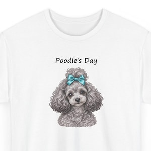 Puede incluir: Una camiseta blanca con el gr&aacute;fico de un caniche gris de pelo rizado con un lazo azul brillante en la cabeza. Sobre el caniche, el texto Poodle's Day est&aacute; impreso en una fuente negra sencilla. El dise&ntilde;o est&aacute; centrado en el pecho.